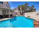 Sparkling pool with rock feature, covered patio, and lush landscaping create a backyard oasis at 9516 Belgate Ct, Las Vegas, NV 89129