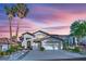 Inviting two-story home with a three-car garage, mature landscaping, and a tile roof set against a vibrant evening sky at 9705 Cameo Rose Ln, Las Vegas, NV 89134
