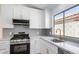 This renovated kitchen includes stainless steel appliances, white cabinets, and a window over the sink at 10482 Clarion River Dr, Las Vegas, NV 89135