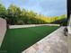 A large backyard features synthetic turf, stone accents, and mature trees at 11318 San Arezzo Pl, Las Vegas, NV 89141