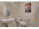 Neat half bathroom featuring a pedestal sink, round mirror, toilet, and Albuquerque Museum wall art at 11919 Jersey Lilly St, Las Vegas, NV 89183