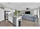 Bright open-concept with a large island flowing into a living room with sleek gray sectional sofa at 12341 Ferry Glide Ave, Las Vegas, NV 89138