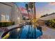 Backyard with rock-lined pool, spa, palm trees, and the home's stucco exterior at dusk at 2024 Spruce Brook Dr, Henderson, NV 89074