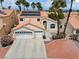 Beautiful two-story home featuring a three-car garage, terra cotta roof, solar panels, and mature palm trees at 2024 Spruce Brook Dr, Henderson, NV 89074