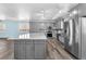 Updated kitchen with gray cabinets, stainless steel refrigerator, large island, and modern lighting fixtures at 2268 Alanhurst Dr, Henderson, NV 89052