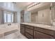 Bright bathroom with dual sinks, granite counters, soaking tub, and a large mirror reflecting the shower at 2293 Sky Island Dr, Henderson, NV 89002