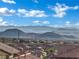 Panoramic view of rooftops and a mountain range under a bright blue sky with scattered clouds at 2749 Invermark St, Henderson, NV 89044