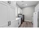 Functional laundry room with modern washer and dryer units, storage cabinets, and tile backsplash at 3131 Reverence Heights Ln, Las Vegas, NV 89138