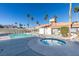 Community pool and hot tub with lounge chairs, a bathhouse, and lush, tall palm trees at 3150 Soft Breezes Dr # 2030, Las Vegas, NV 89128