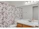 A cozy bathroom, including a toilet, sink, mirror, and a shower with a floral curtain at 349 Clayton St, Henderson, NV 89074