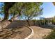 Landscaped backyard with mature trees, stone accents, and covered patio with dining set at 3816 Sunking St, Las Vegas, NV 89130