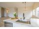 Kitchen island with quartz countertops, a stainless steel sink, and modern faucet under a chandelier at 6124 Desert Haven Rd, Las Vegas, NV 89130