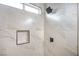Close up of the marble tiled walk in shower with shower caddy and rectangular window for natural light at 6124 Desert Haven Rd, Las Vegas, NV 89130