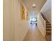 Light-filled hallway featuring tile floors, staircase, and a glimpse of the kitchen with white cabinetry at 6442 Kobe Knoll Ct, Las Vegas, NV 89141