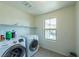 Laundry room showcasing modern washer and dryer units, a window, and tile flooring at 6442 Kobe Knoll Ct, Las Vegas, NV 89141