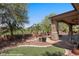 Landscaped backyard featuring artificial turf, covered patio, and desert landscaping at 653 Paloma Cir, Mesquite, NV 89027