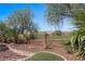 View of the backyard that overlooks the golf course, surrounded by desert landscaping, rock ground cover, and trees at 653 Paloma Cir, Mesquite, NV 89027