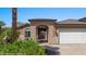 Home exterior featuring a stone archway, manicured landscaping and two-car garage at 653 Paloma Cir, Mesquite, NV 89027