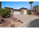View of the front exterior featuring a circular driveway, three-car garage, desert landscaping and unique architectural details at 653 Paloma Cir, Mesquite, NV 89027