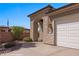 View of the home's front exterior with a three car garage, stone archway entrance, and desert landscaping at 653 Paloma Cir, Mesquite, NV 89027