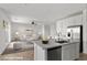 Open kitchen with stainless steel appliances, island with sink, and a view to the living room with lots of light at 6854 Chargehand Ave, Las Vegas, NV 89156