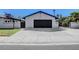 A detached garage with a black door, a white exterior, and a wide, spacious driveway at 819 Bracken Ave, Las Vegas, NV 89104