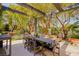 Covered patio with dining area and BBQ, surrounded by mature trees and landscaping at 9500 Balatta Canyon Ct, Las Vegas, NV 89144