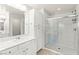 Bright bathroom with double sinks, white cabinets, and a tiled walk-in shower at 160 Lomita Heights Dr, Las Vegas, NV 89138