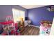 A cozy purple bedroom with laminate flooring, natural light, and furnishings at 2722 Sweet Basil Dr, Las Vegas, NV 89142