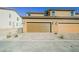 Exterior view of a two-car garage with brown doors and a brick driveway under a clear blue sky at 3240 Avernus Ave, Henderson, NV 89044