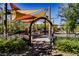 Community playground in a fenced area with colorful shades offers a safe and engaging play area for children at 3240 Avernus Ave, Henderson, NV 89044