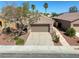 Home's exterior featuring a two-car garage, mature landscaping, and xeriscaping in the front yard at 4124 Gliding Gulls Ave, North Las Vegas, NV 89084