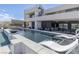 Beautiful backyard with a long swimming pool, lounging chairs, and an outdoor kitchen area at 53 Falling Ridge Ln, Henderson, NV 89011