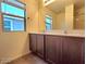 Bathroom featuring double sinks, dark wood cabinets and a window at 5817 Bonita Rose St, Las Vegas, NV 89113