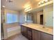 Bright bathroom with double sink vanity, large mirror and bathtub with tile surround at 5817 Bonita Rose St, Las Vegas, NV 89113
