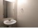 A pedestal sink, square mirror and neutral walls are highlighted in this half-bath at 6168 Scarlet Leaf St, Las Vegas, NV 89148
