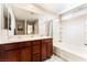 Bathroom with double vanity, large mirror, shower-tub combo and white tiled walls at 6650 Drusilla St, North Las Vegas, NV 89084