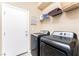 Well-equipped laundry room featuring modern washer and dryer, convenient shelving and a bright white door at 6650 Drusilla St, North Las Vegas, NV 89084