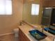 Bathroom features dual windows, granite countertop and a blue glass bowl sink at 7840 Millhopper Ave, Las Vegas, NV 89128