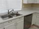 Well-lit kitchen sink and dishwasher with quartz countertops and white cabinetry at 7840 Millhopper Ave, Las Vegas, NV 89128
