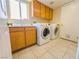 Well-lit laundry room with washer, dryer, sink, and wooden cabinets at 7840 Millhopper Ave, Las Vegas, NV 89128