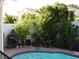 Backyard pool area with an outdoor fireplace and lush greenery, perfect for entertaining at 7840 Millhopper Ave, Las Vegas, NV 89128