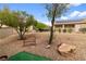 Fully landscaped backyard featuring desert landscaping, mature trees, and rock accents at 7934 Kiskadee St, North Las Vegas, NV 89084
