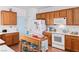 Functional kitchen featuring wooden cabinets, white appliances, and a central island at 7934 Kiskadee St, North Las Vegas, NV 89084