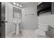 Bathroom featuring pedestal sink, toilet, black cabinet, and large mirror at 8029 Chablis Bay St, Las Vegas, NV 89131