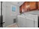 Laundry room features white washer and dryer, wood cabinets, and a window at 8029 Chablis Bay St, Las Vegas, NV 89131