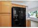 Kitchen with black refrigerator, wood cabinetry and view to the breakfast nook at 8901 Kingsmill Dr, Las Vegas, NV 89134