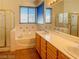 Bathroom featuring a double sink vanity, tub, walk-in shower, and tiled floor at 8940 Emery Lake St, Las Vegas, NV 89123