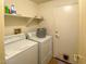 A well-lit laundry room featuring a washer, dryer, storage shelf, and tiled flooring at 8940 Emery Lake St, Las Vegas, NV 89123