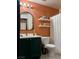 Charming bathroom with a clean vanity, mirror, and shelving, complemented by an orange accent wall at 10403 Fancy Fern St, Las Vegas, NV 89183